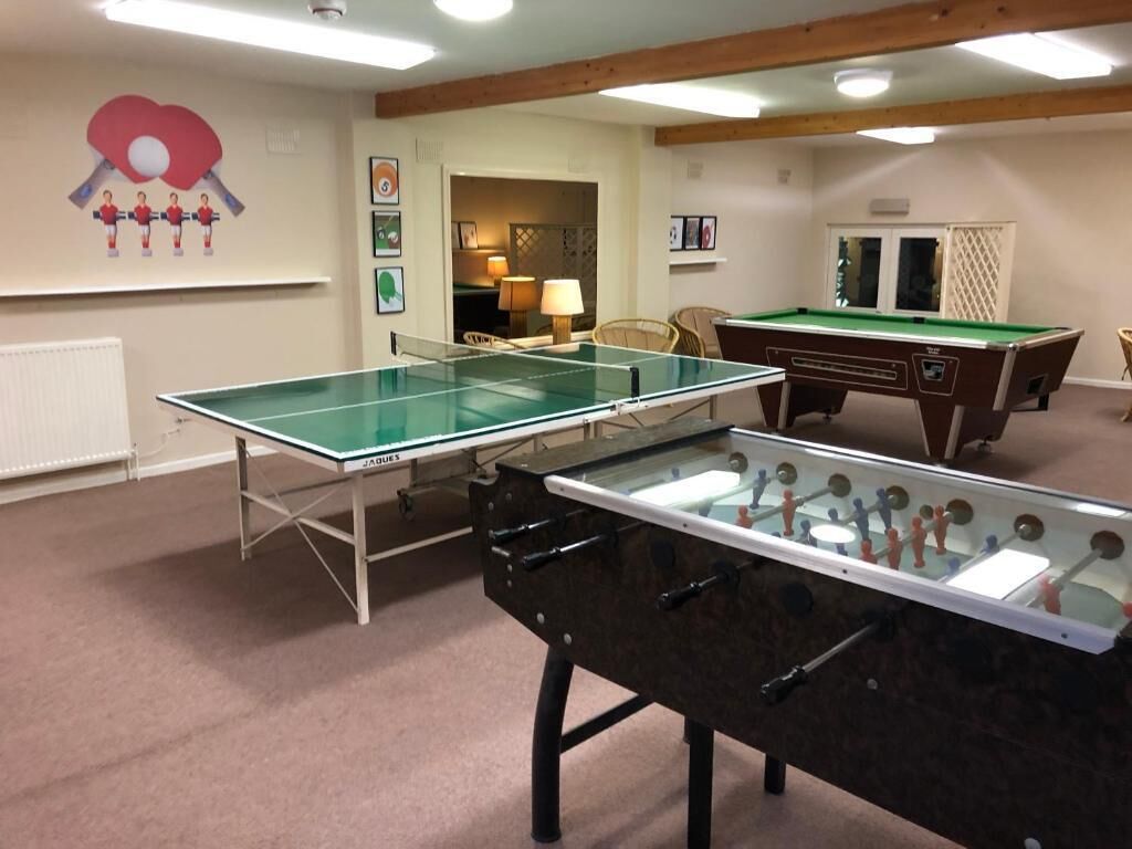 A room with a foosball table, a ping pong table, and a pool table.