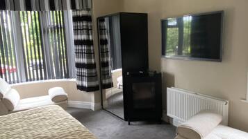 Habitación de hotel con cama, televisor, chimenea y ventana con cortinas.