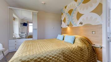 Une chambre d’hôtel avec un grand lit, une armoire, un miroir et un mur décoratif.