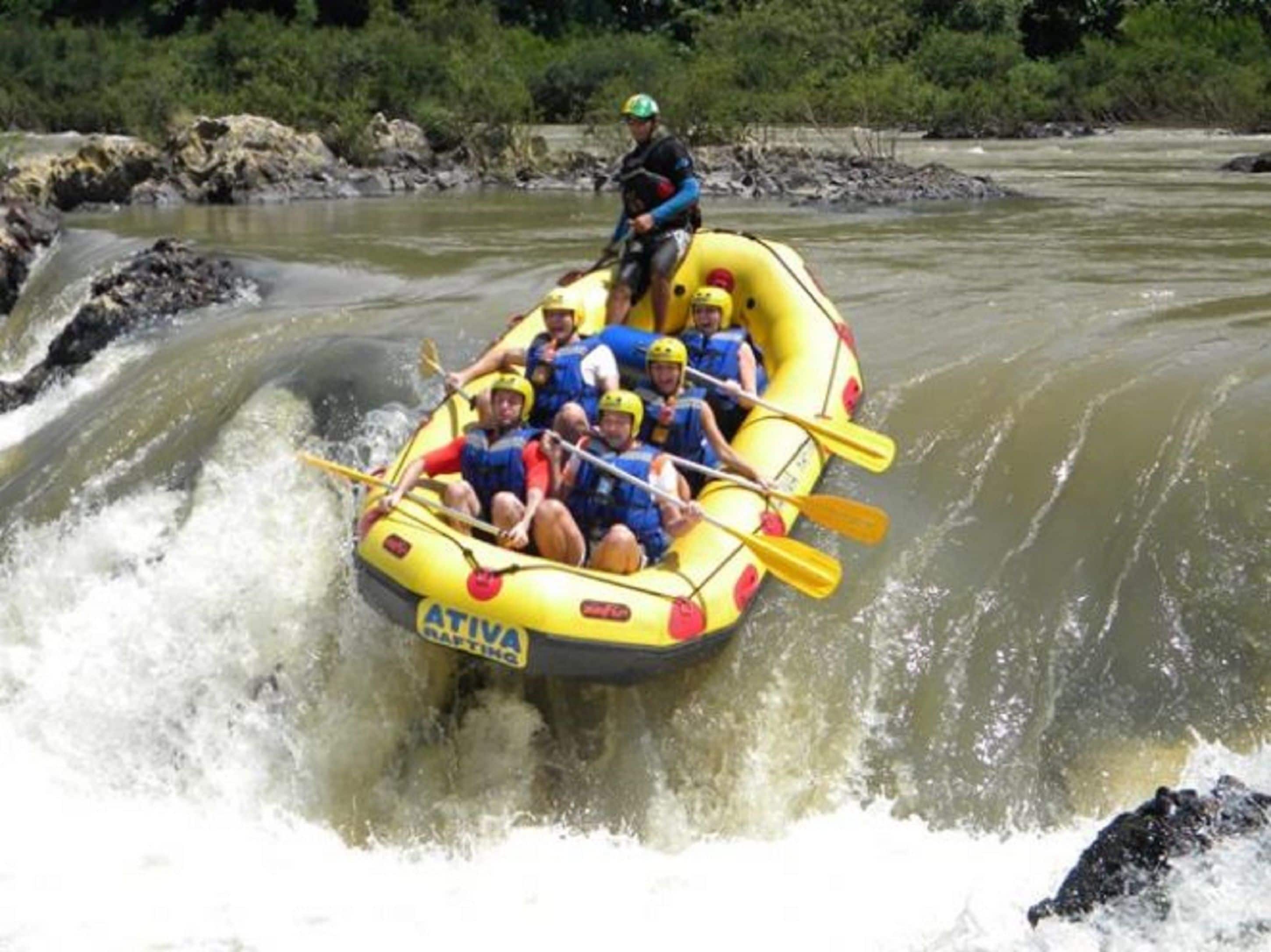 Un grupo de personas en una balsa inflable amarilla navega por un río con rápidos.