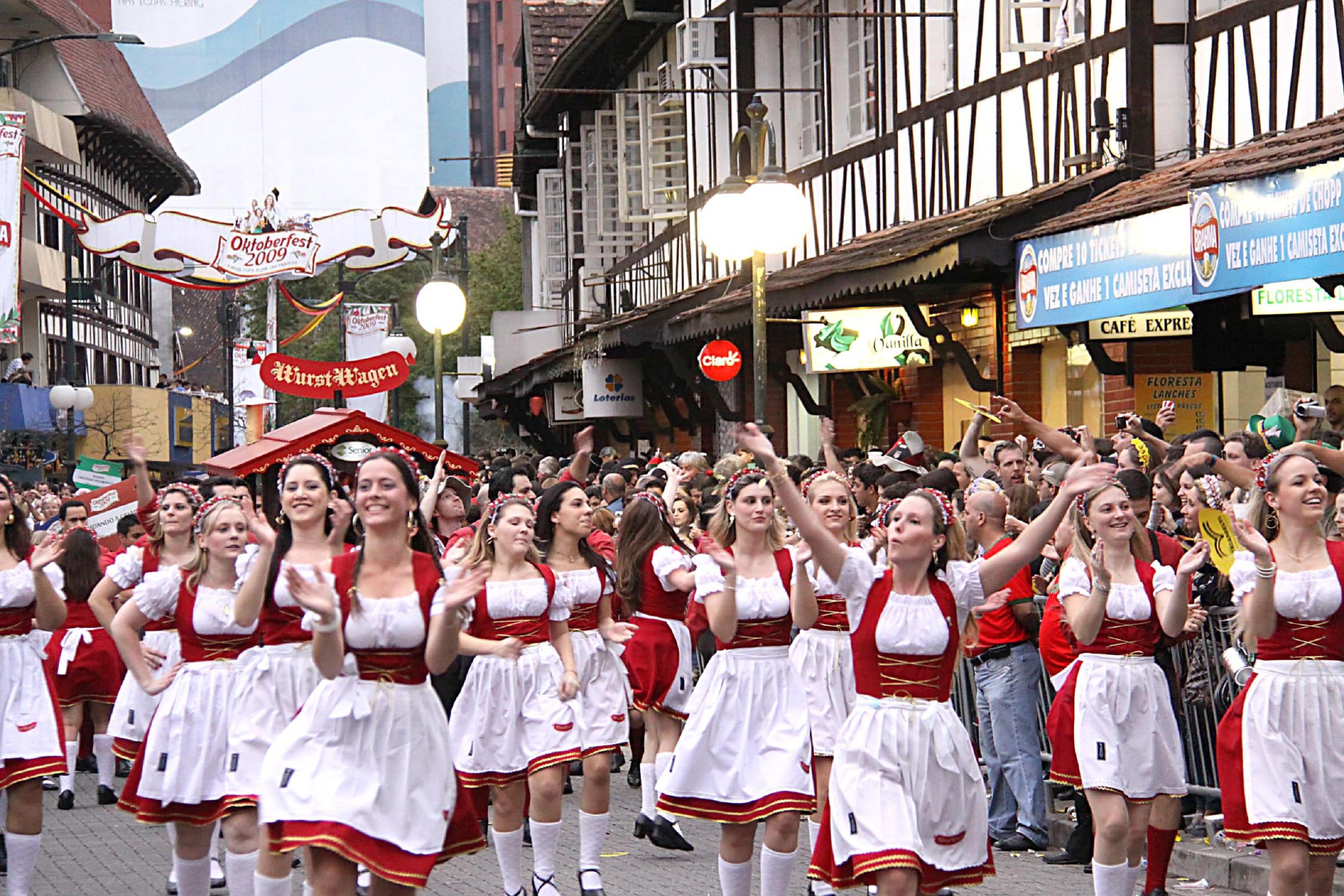 Escena callejera con bailarines bávaros vestidos con trajes rojo y blanco.