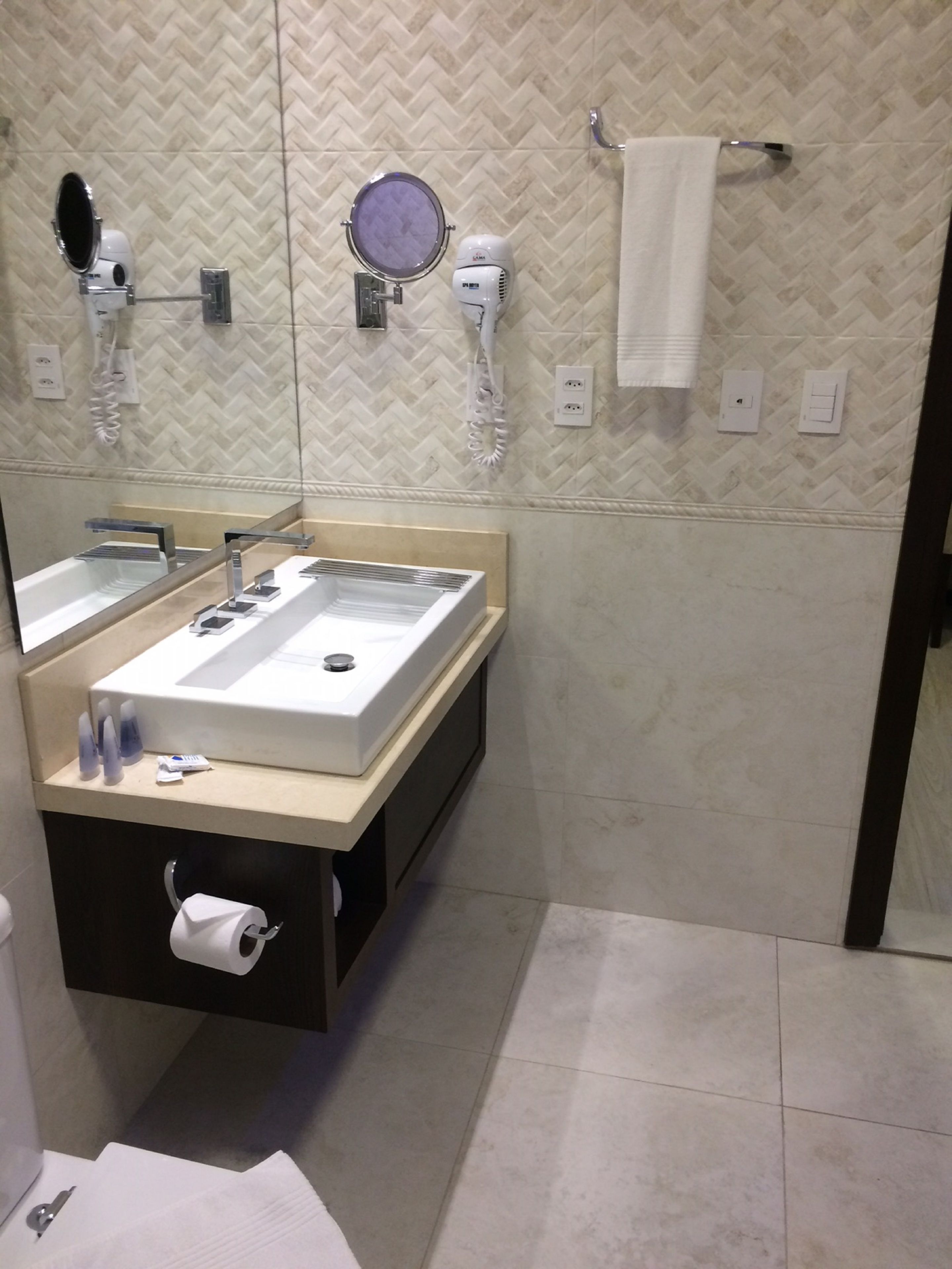 Un baño moderno con un espejo grande, un lavabo y un perchero para toallas.