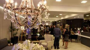 Un candelabro con múltiples brazos y adornos de cristal en una habitación bien iluminada, con mucha gente.