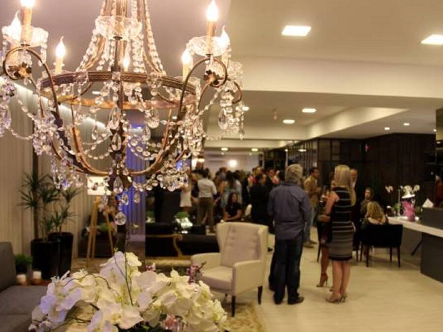 A chandelier with multiple arms and crystal decorations in a well-lit room with a crowd of people.