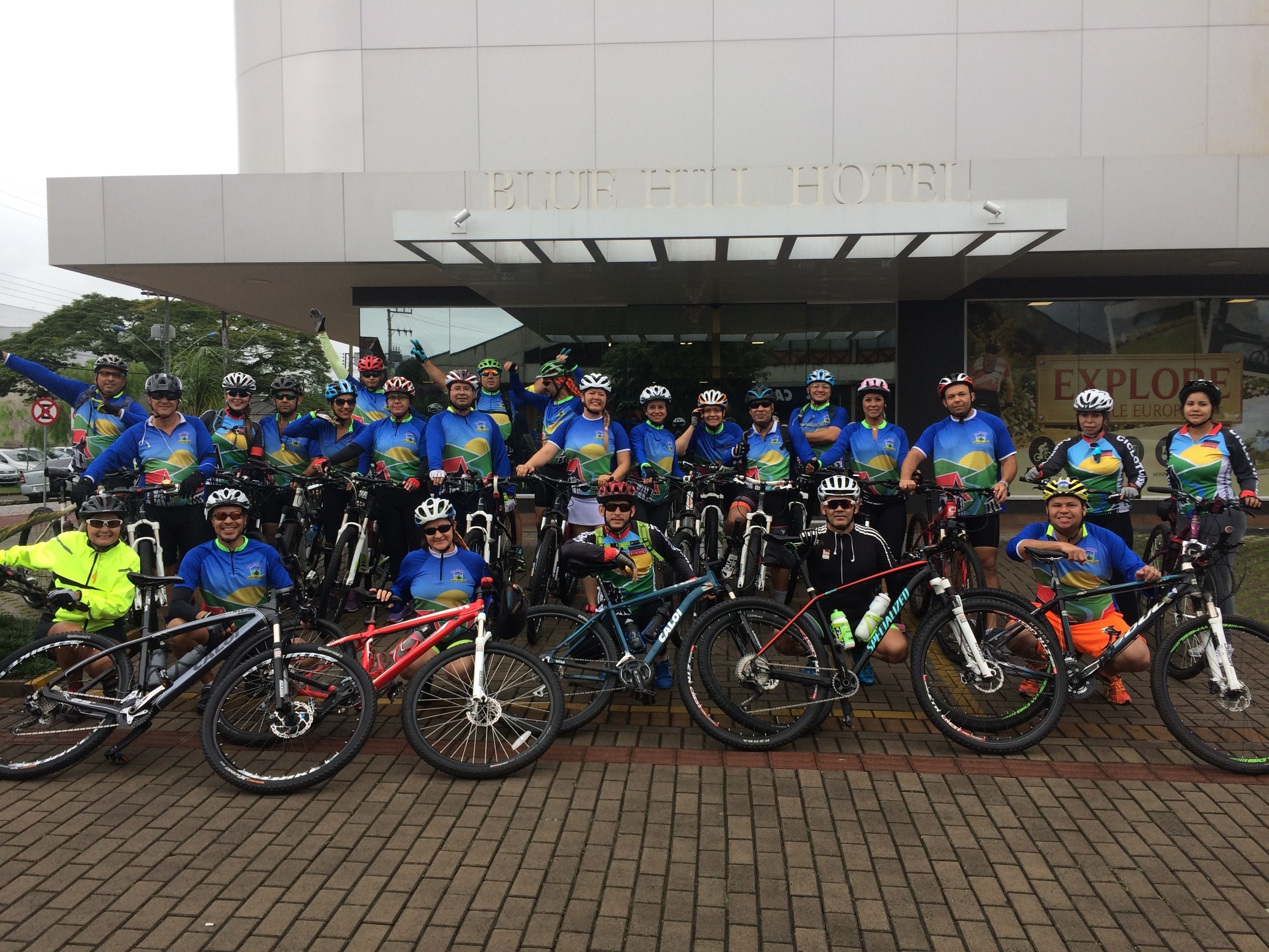 A group of cyclists posing in front of a building with a sign that reads "BLUE HILL HOTEL".