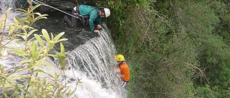 A person rappelling down a waterfall with a rope.