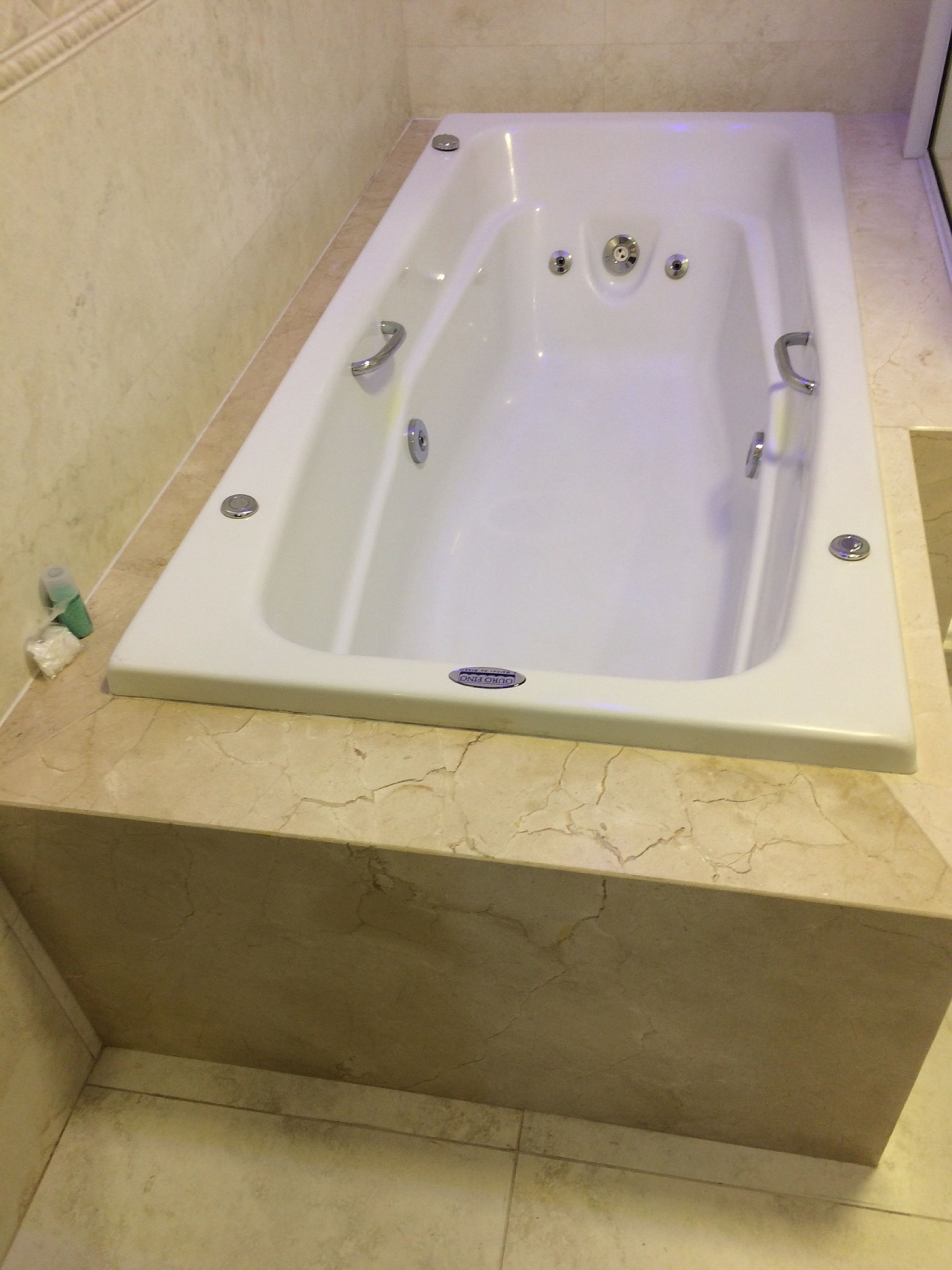A rectangular bathtub with a single drain, two faucets, and a control panel.