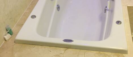 A rectangular bathtub with a single drain, two faucets, and a control panel.