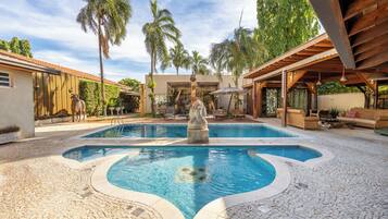 Una piscina al aire libre, sombrillas, sillones reclinables de piscina