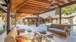 Un espace extérieur couvert, aménagé comme un patio, avec des meubles en osier, une piscine et un coin repas.