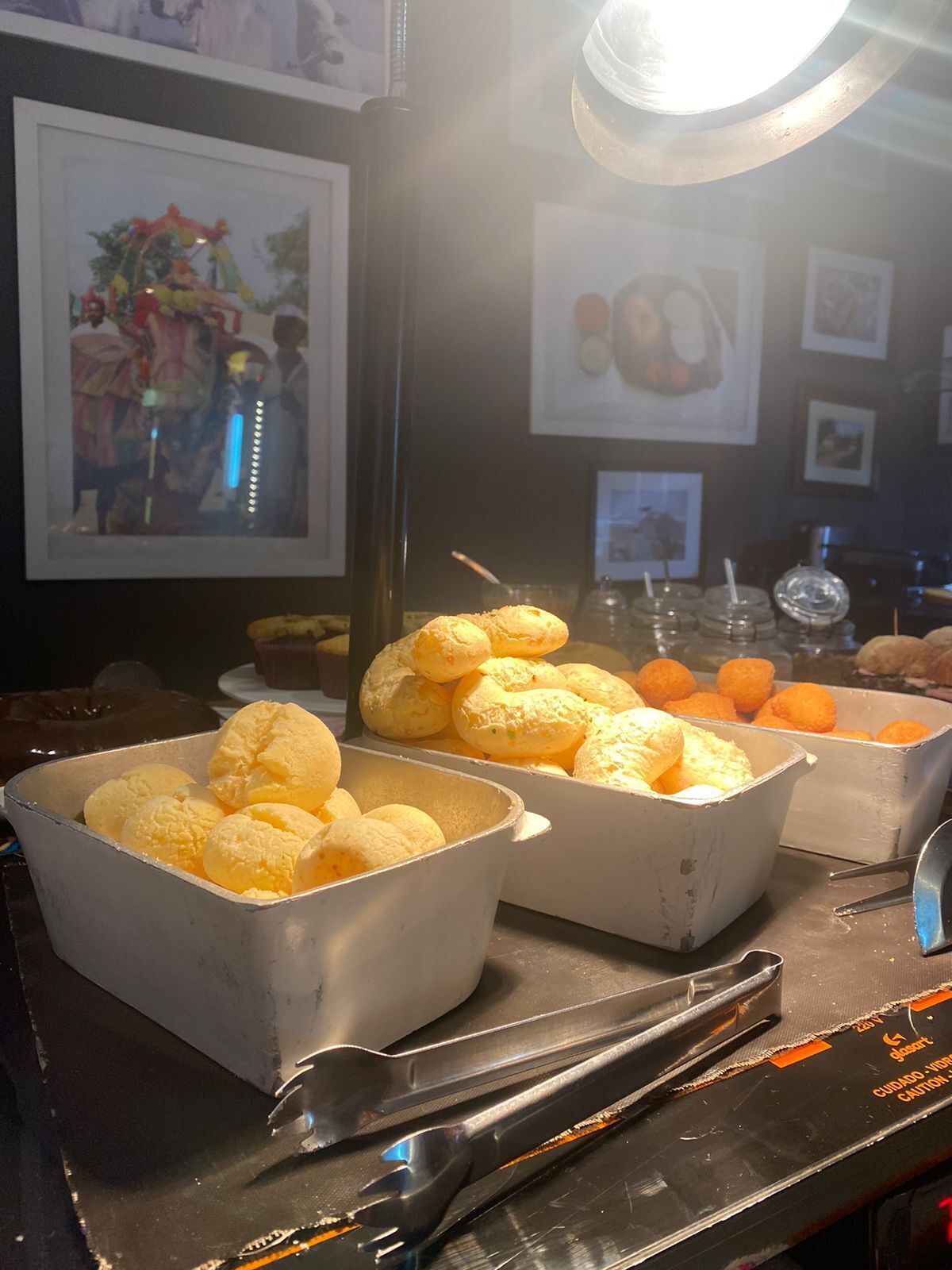 Una mesa de buffet con diversos alimentos, incluyendo postres amarillos y pasteles de naranja, bajo una luz brillante.