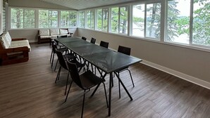 A spacious room with a long table and chairs, large windows, and a ceiling with linear patterns. - Pinedale Inn (Gravenhurst)