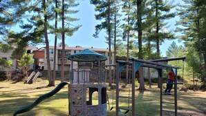 A playground with a climbing structure, slides, and swings. - Pinedale Inn (Gravenhurst)
