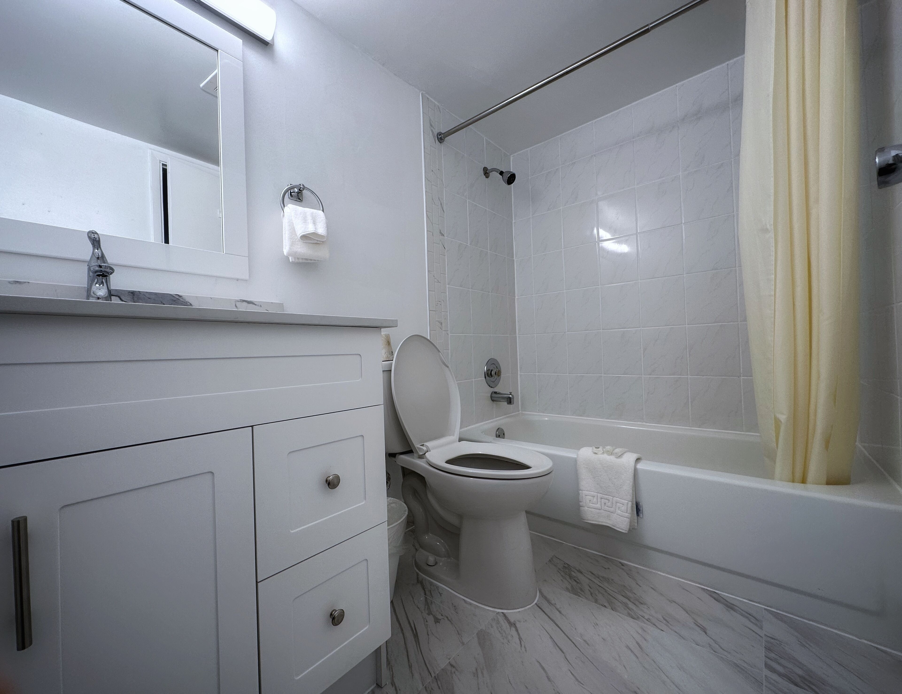 A modern bathroom with a toilet, sink, and bathtub.