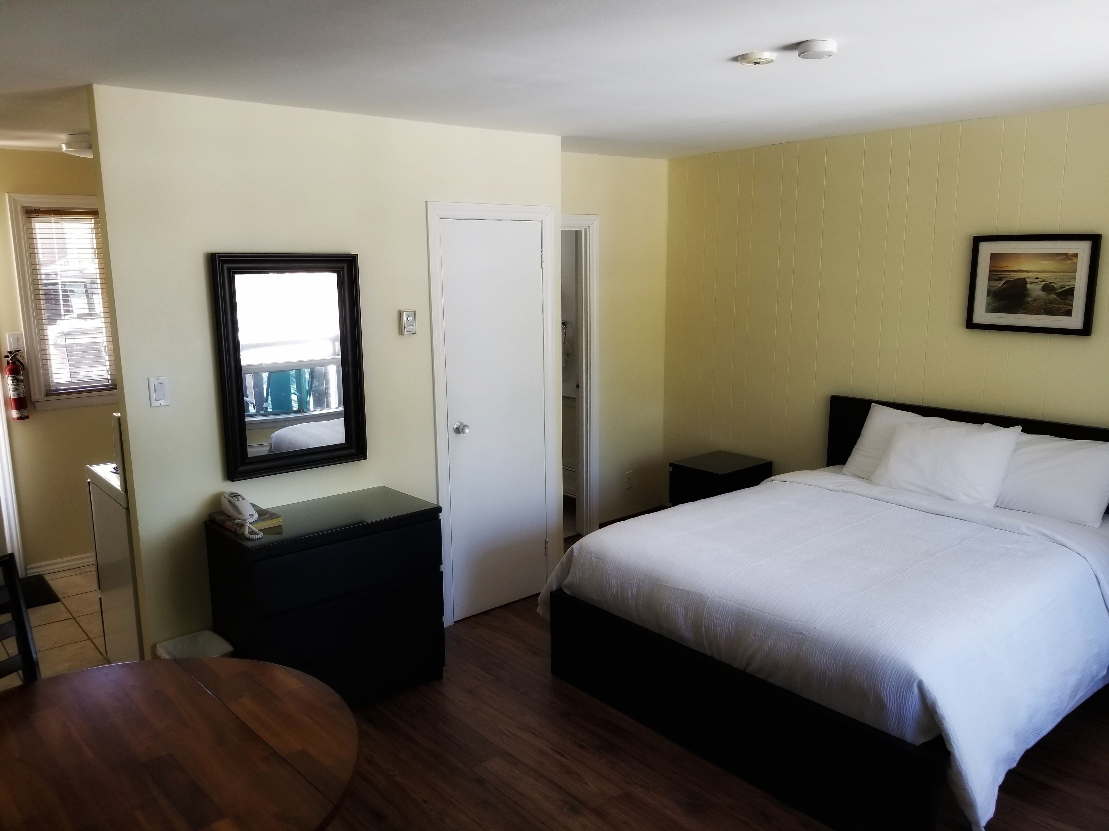 Quarto com cama, mesas de cabeceira, espelho e uma mesinha.