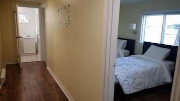 A bedroom with a bed, a window, and a bathroom visible through an open door.