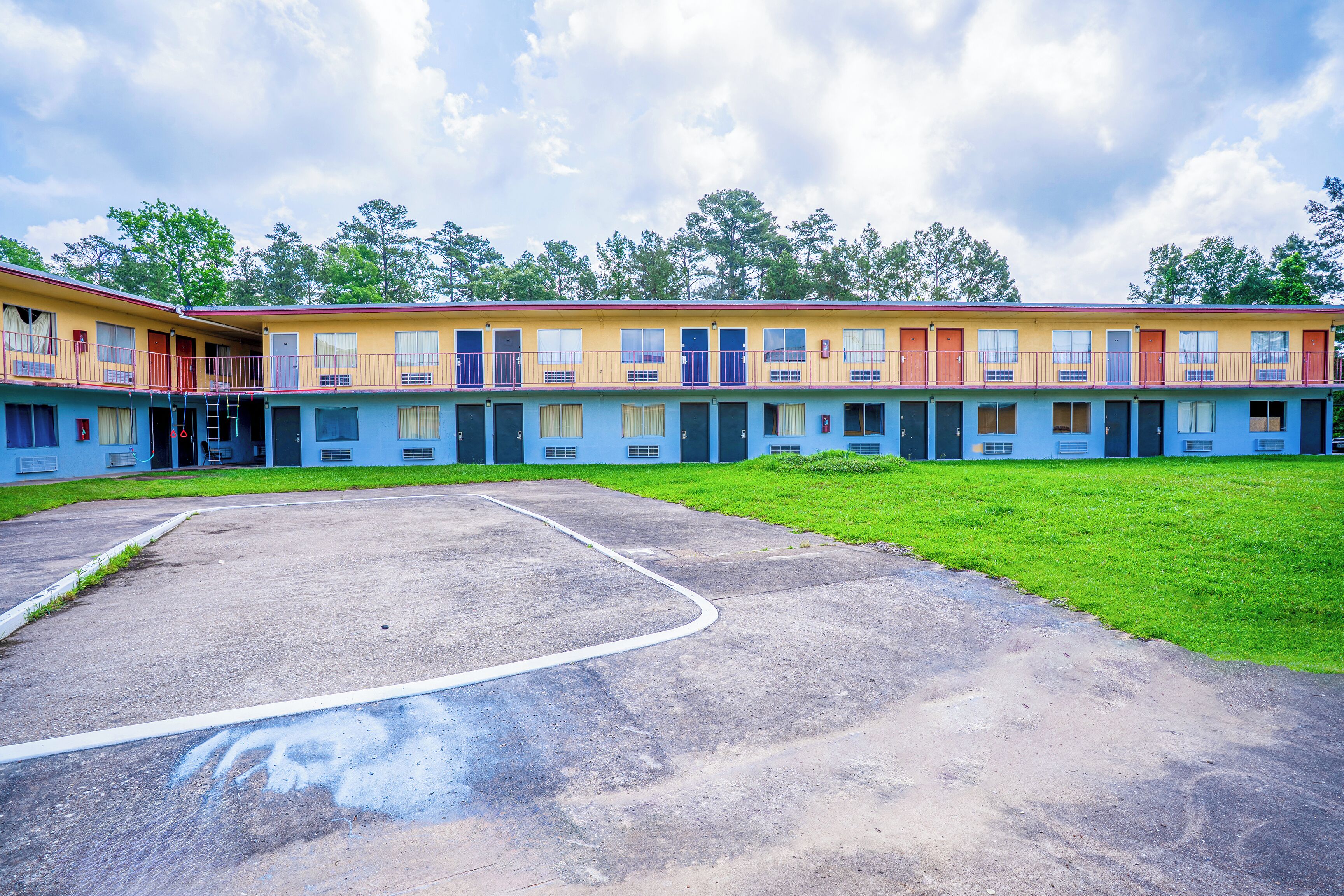 A row of motel buildings with a parking lot in front.
