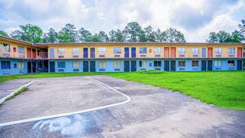A row of motel buildings with a parking lot in front.