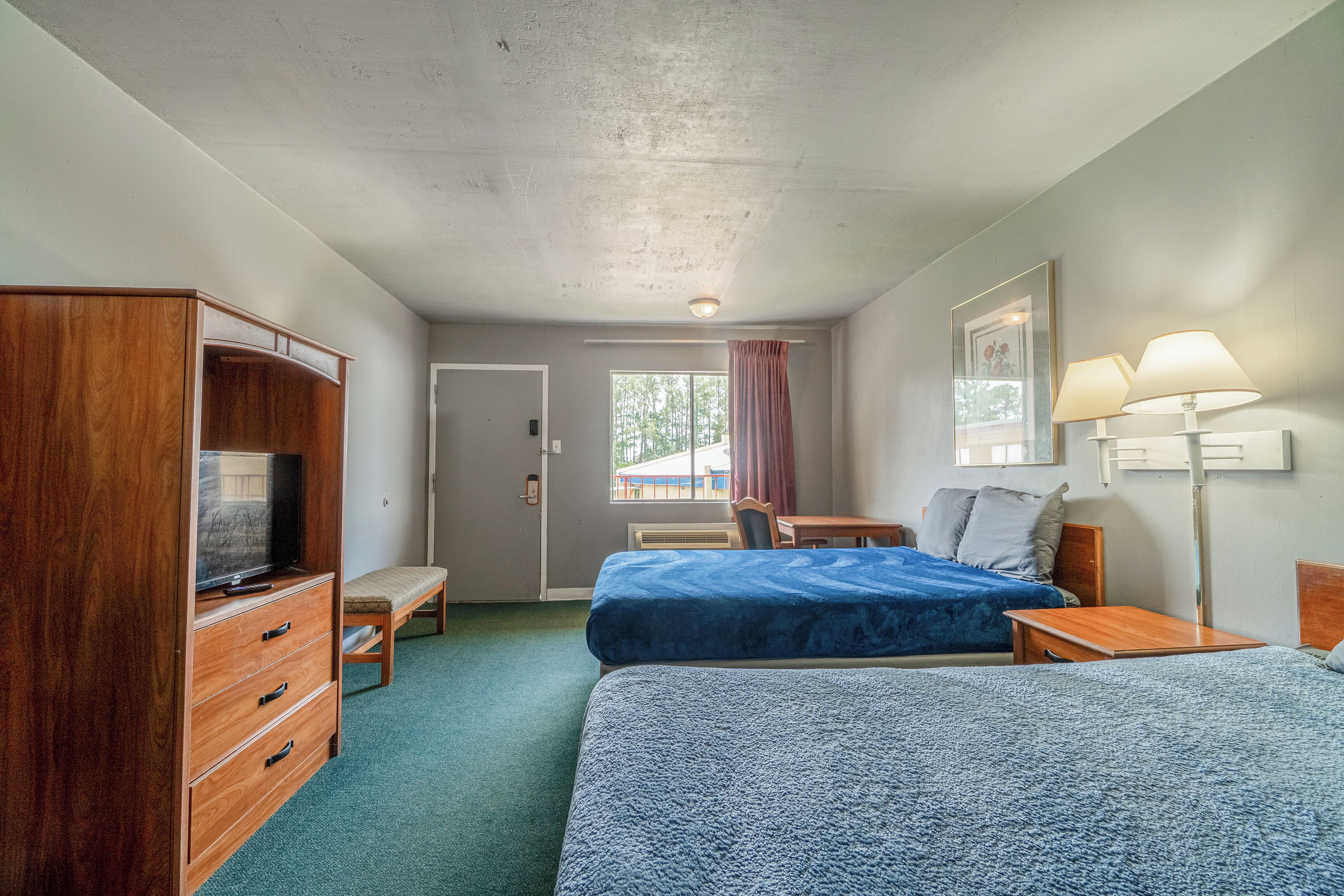 Habitación de hotel con dos camas, un escritorio, un televisor y un armario.