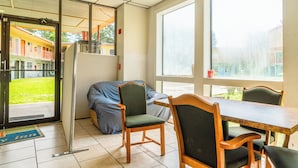 A room with a wooden table and chairs, a sofa, and a large window. - Economy Inn Livingston By OYO TX US 59 (Livingston)