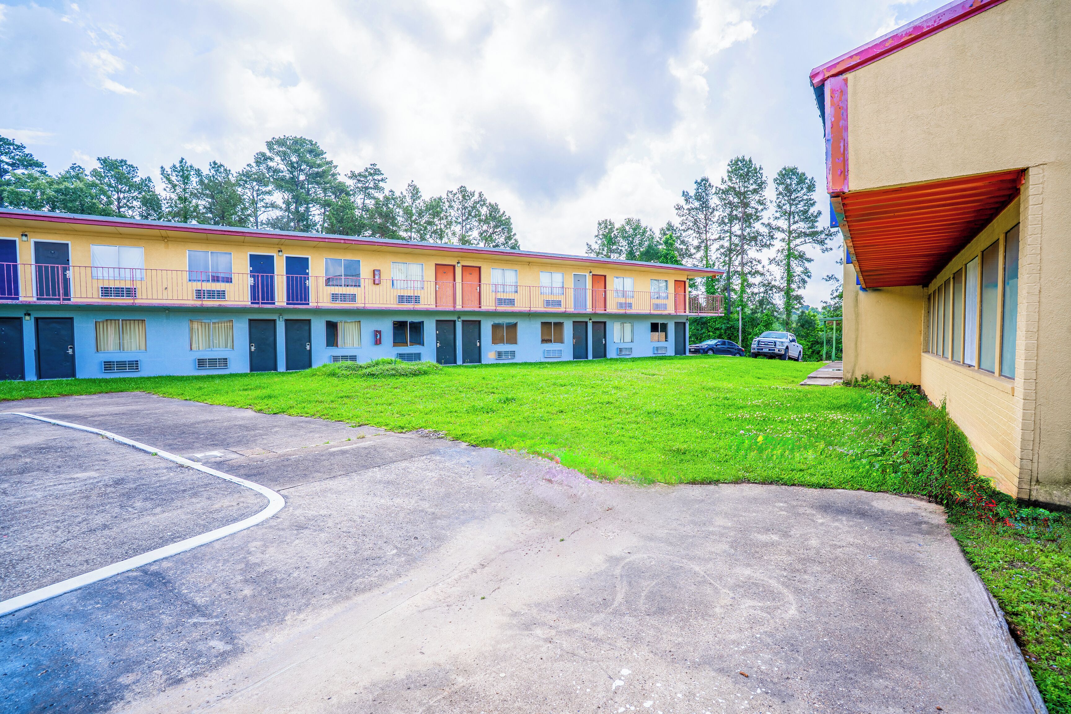 En række motelbygninger med parkeringsplads foran.