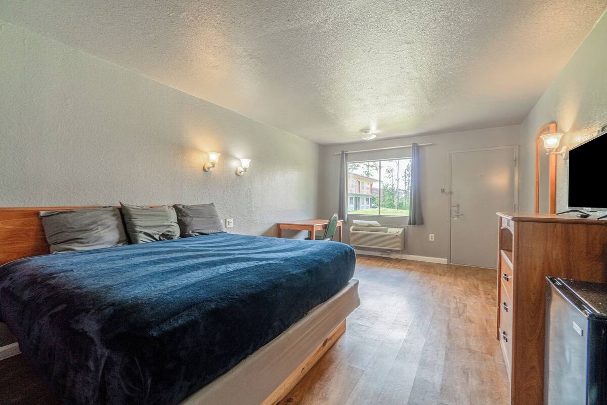 Un dormitorio con cama, mesitas de noche, cómoda y ventana con vistas.