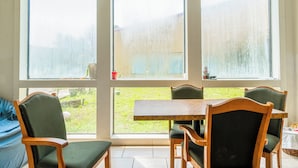 A room with a large window, a wooden table, and four chairs. - Economy Inn Livingston By OYO TX US 59 (Livingston)