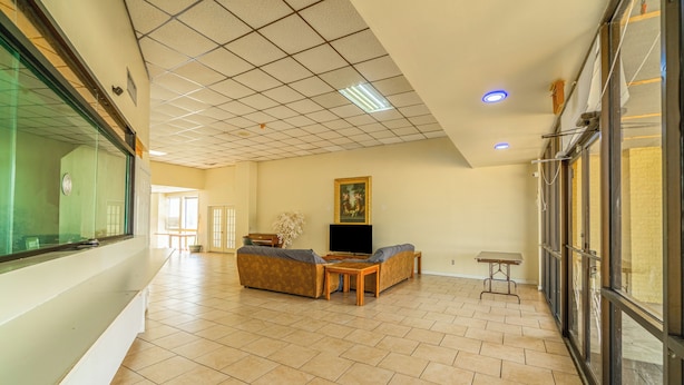A spacious living area with a sofa set, a television, and a small table. - Economy Inn Livingston By OYO TX US 59 (Livingston)