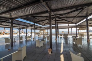 An outdoor patio with tables and chairs, a covered area with a view of the beach, and umbrellas. - Hotel Tmk Marine Beach (Djerba Midun)