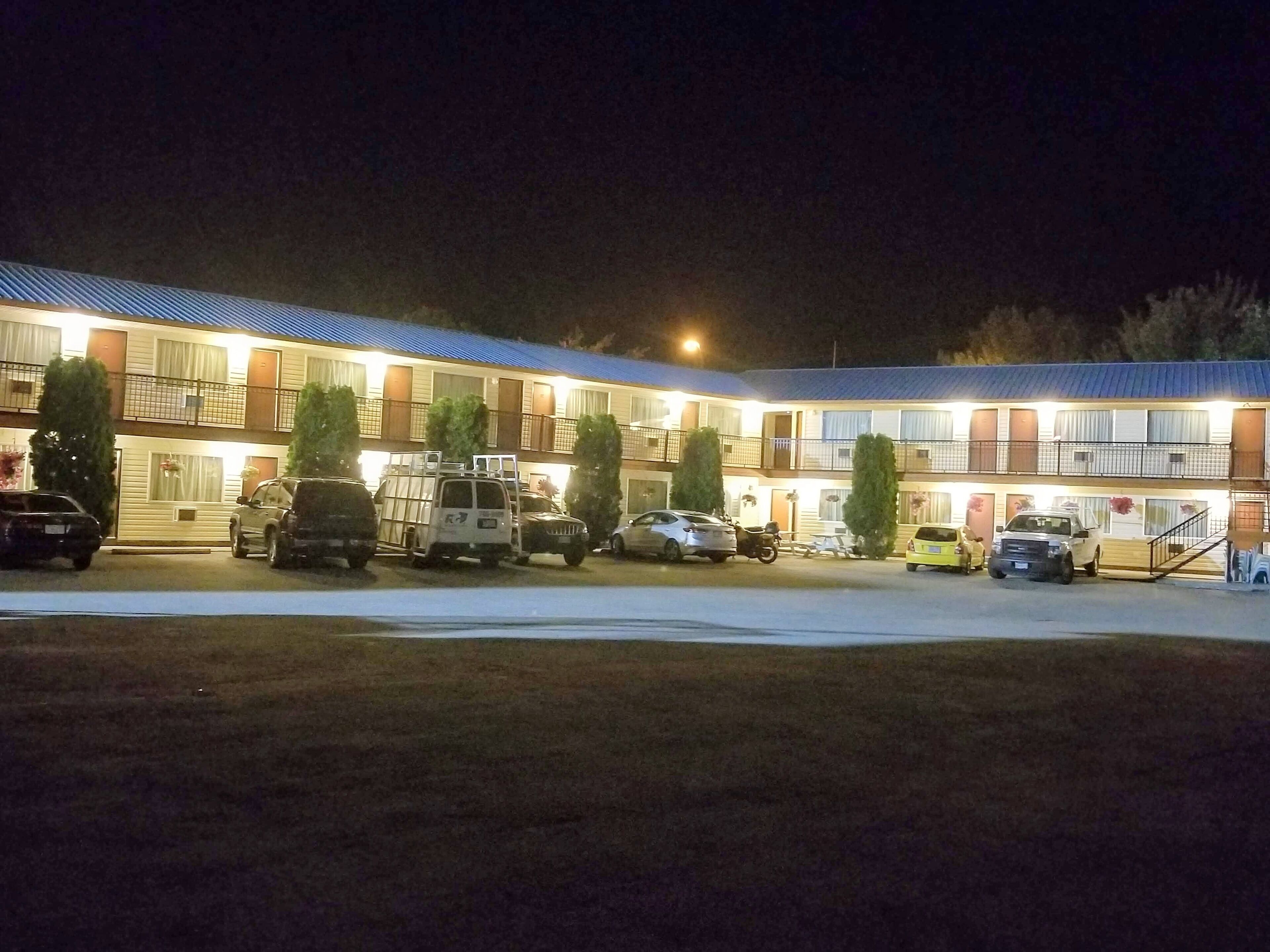 Un motel doté de nombreuses places de stationnement, d’un parking couvert et d’un bâtiment avec un toit bleu.