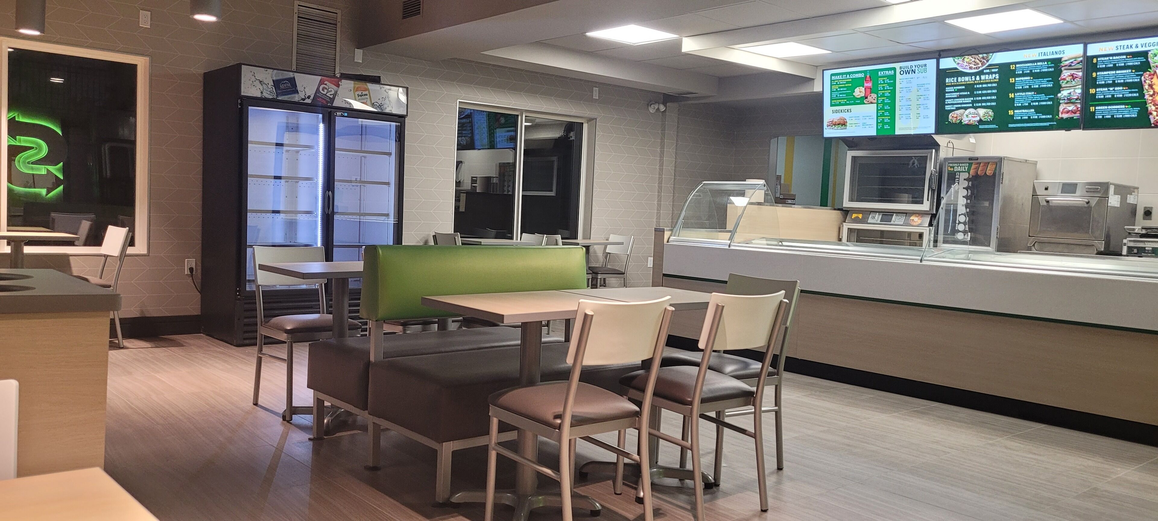 Un restaurante con cabinas, una barra y un panel con la carta.