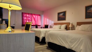 Une chambre d’hôtel avec deux lits, un bureau avec une lampe, une chaise, un cadre et un tableau accroché au mur.