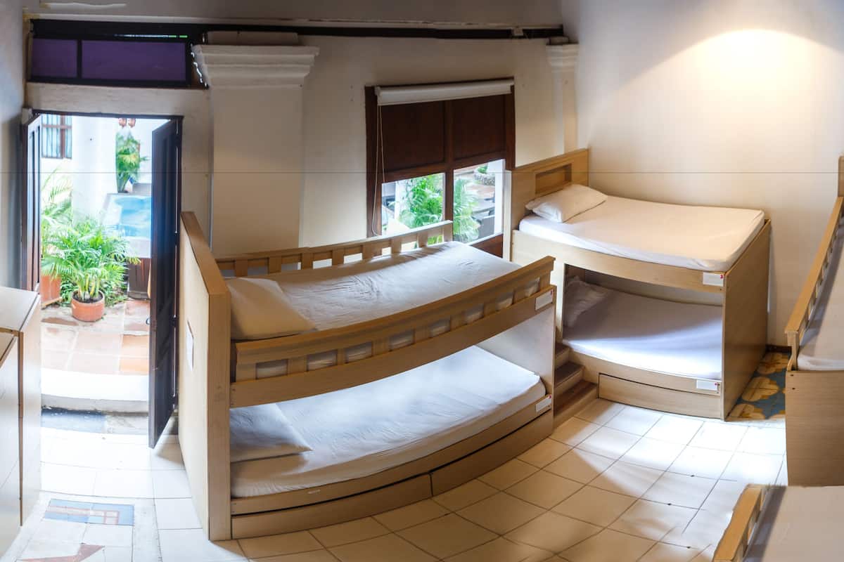 A compact room with bunk beds, a window with a view of greenery, and a door leading outside.