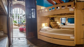 A bunk bed room with a curved design, a small desk, and a window with a view of the outside. - La Villana Hostel (Santa Marta)