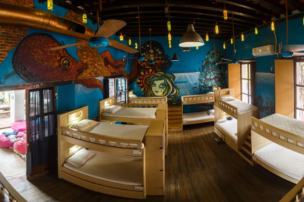 A room with bunk beds, a mural, and hanging lights.
