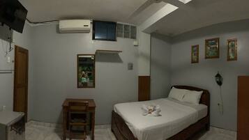 A bedroom with a bed, a wooden nightstand, a small table, a mirror, and a wardrobe.