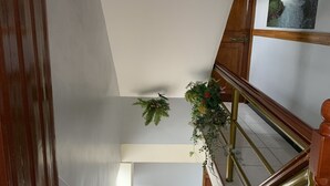A staircase with wooden railings and a handrail, leading to a landing with a large wall-mounted picture. - Hostal Ventura Isabel (Iquitos)
