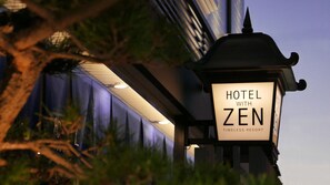 Señal de hotel con el nombre "HOTEL WITH ZEN" y el lema "TIMELESS RESORT".