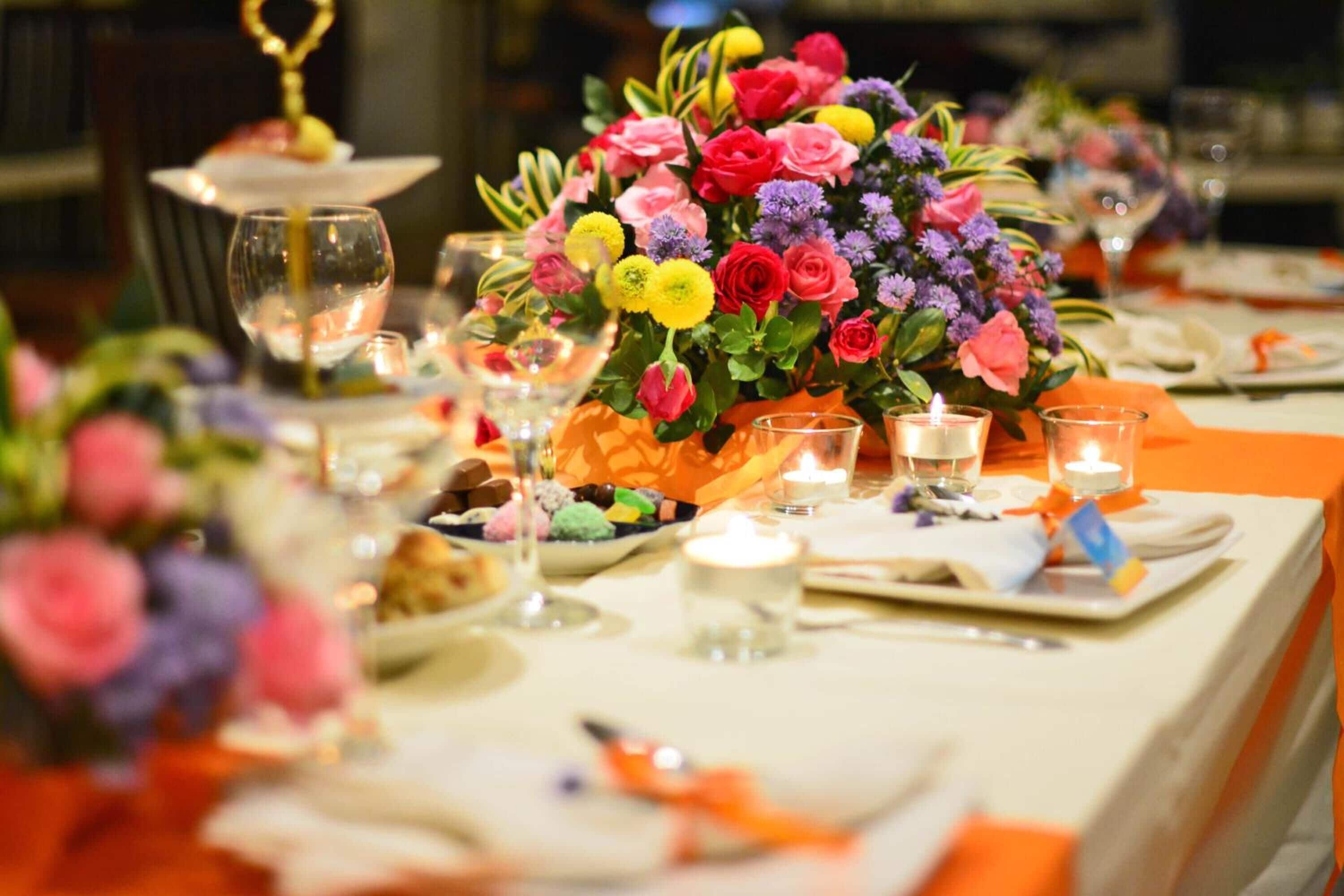 A table set with a floral centerpiece, candles, and a variety of dishes.