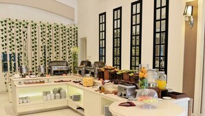 Disposição de buffet com diversos alimentos, uma máquina de café e um dispensador de suco.