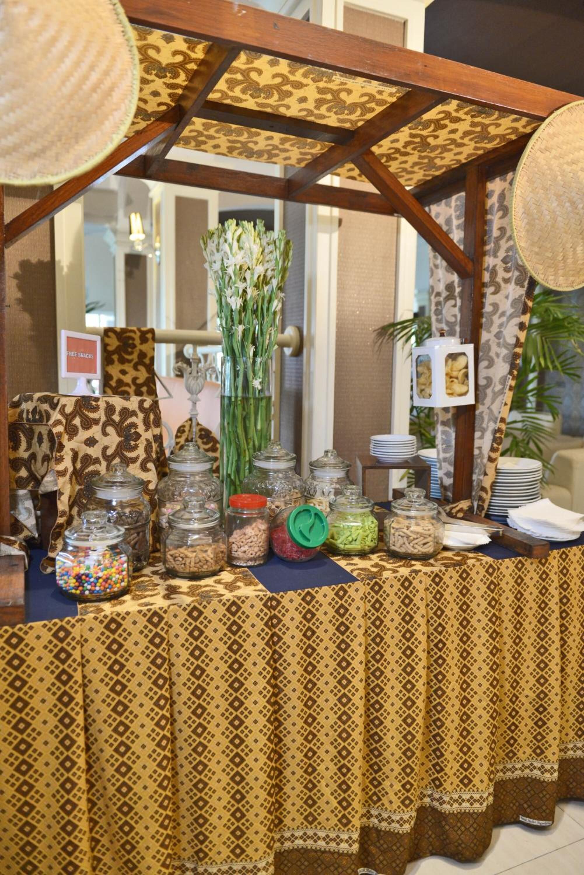 A buffet setup with patterned tablecloths, glass jars of food, and a decorative centerpiece.