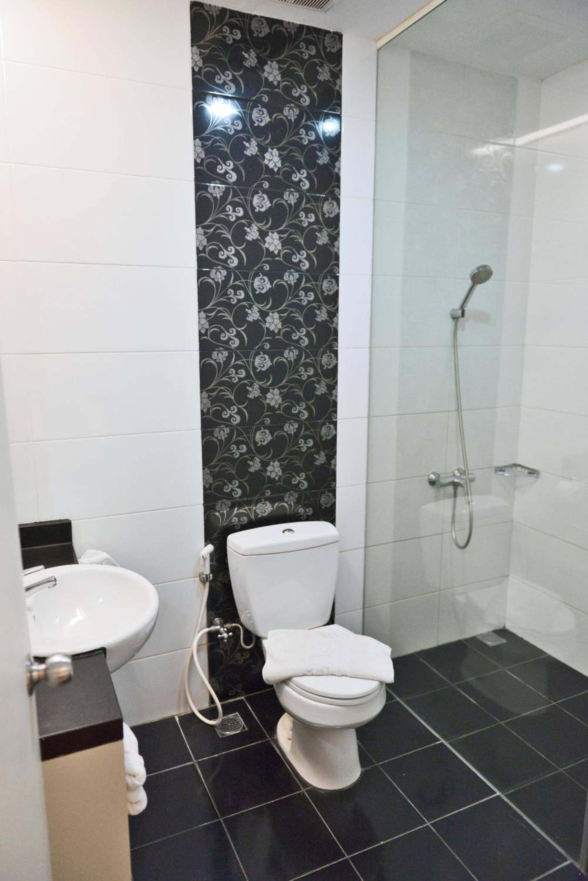 A bathroom with a toilet, bidet, and glass-enclosed shower.