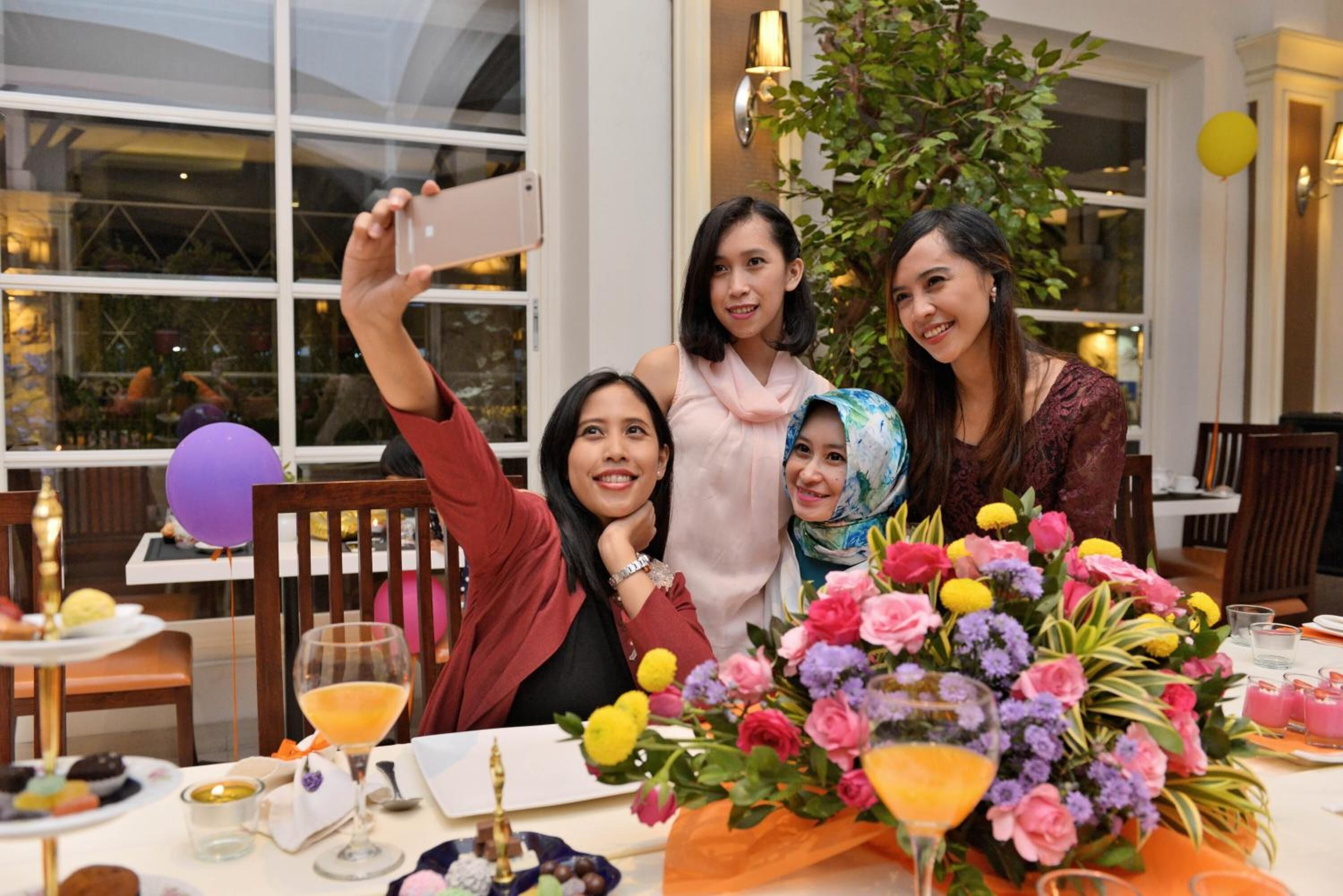 A group of people seated at a table with a floral centerpiece, a glass of orange juice, and a dessert plate.