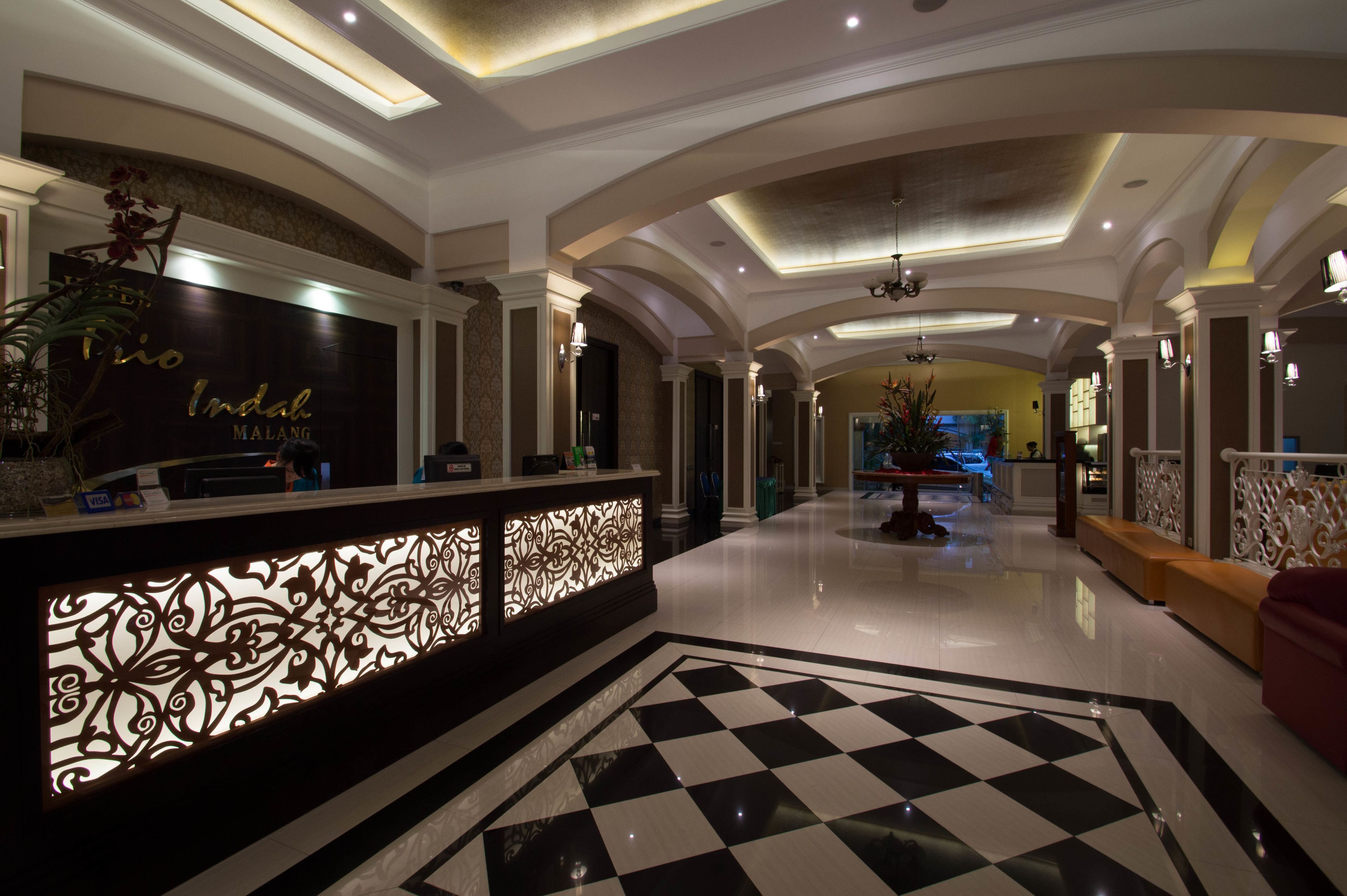 Un hall de hotel con mostrador de recepción, suelo a cuadros y diseño de techo moderno.