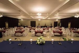 Un salón de banquetes con mesas redondas cubiertas con manteles blancos, dispuestas en filas.
