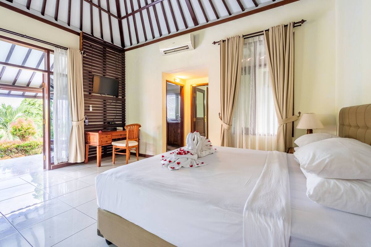 A hotel room with a large bed, a desk, a chair, and a TV.
