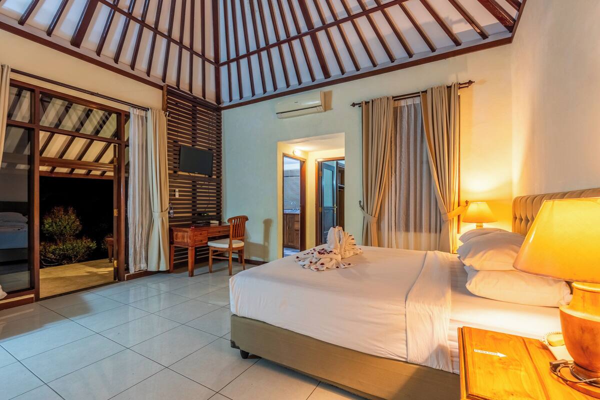 A hotel room with a bed, a desk, a chair, and a TV.