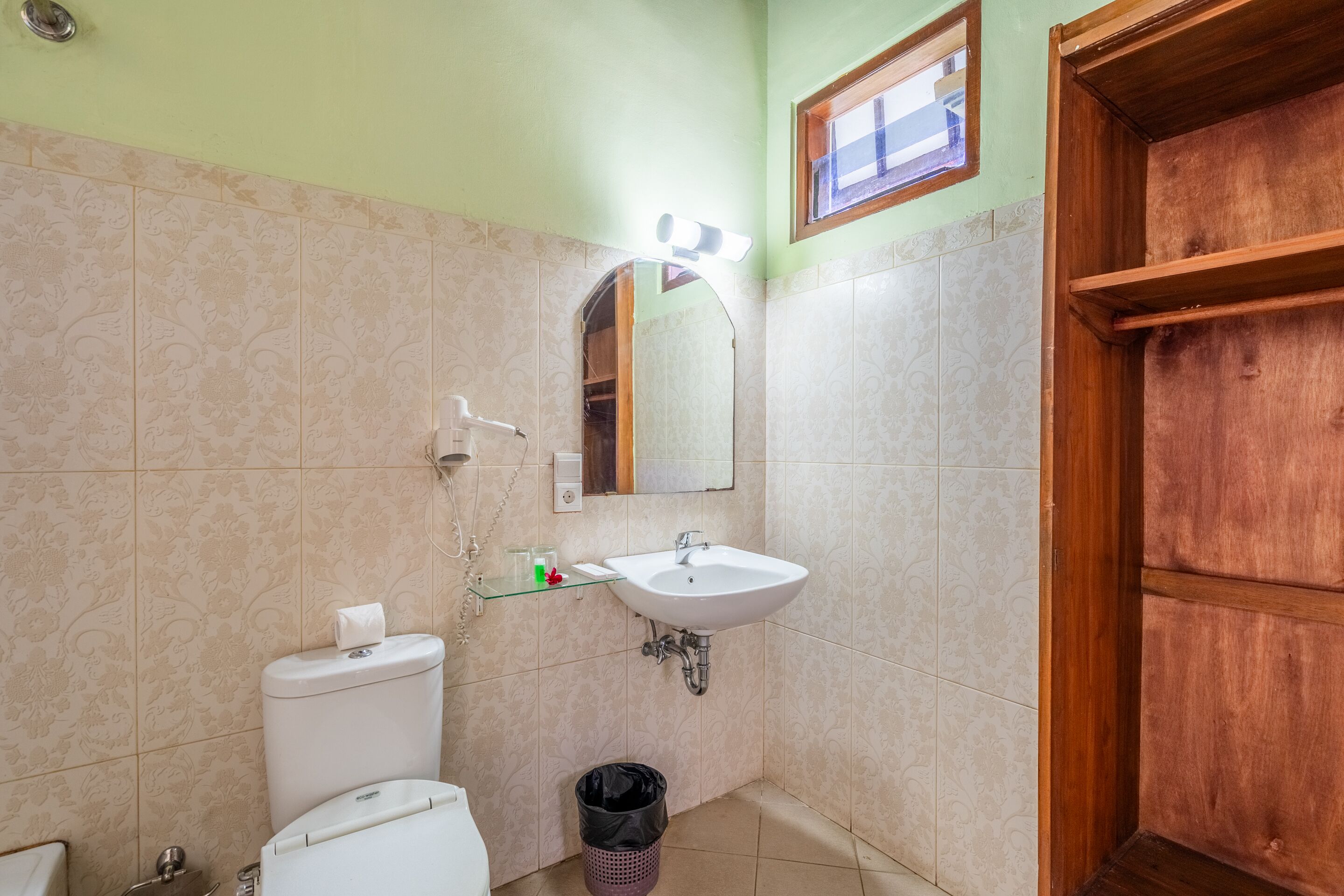 Un baño con lavabo blanco, un espejo, un inodoro y una puerta de madera.