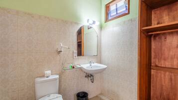 Un baño con lavabo blanco, un espejo, un inodoro y una puerta de madera.