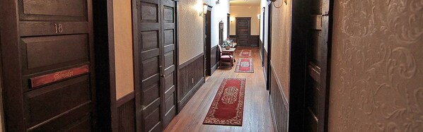 A hallway with wooden doors, a red carpet, and a small table with chairs.